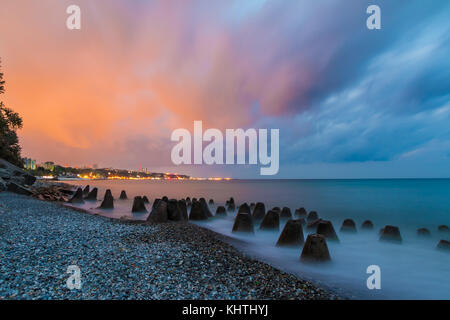 Una lunga esposizione foto del calcestruzzo massi conica giacente in mare sullo sfondo della costa di sochi all'alba, Russia Foto Stock