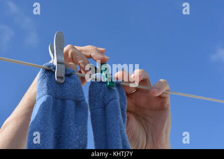 Donna di stendere il bucato, close up di mani, calzini e mollette Foto Stock