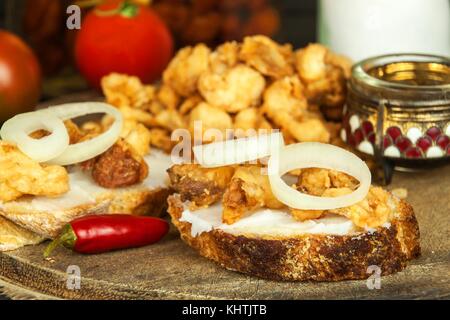 Cumulo di domestici fritto salato di ciccioli di maiale grasso. Il cibo spazzatura. i ciccioli di maiale sulla scheda di cucina Foto Stock
