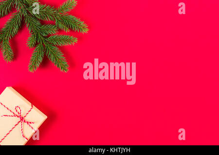 Composizione di natale su sfondo rosso. Verde abete del ramo e presente nella casella Foto Stock