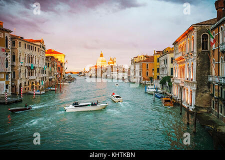 Vista dal Ponte dell'Accademia su barche e le gondole del Canal Grande di Venezia in un giorno nuvoloso durante il tramonto incandescente Foto Stock