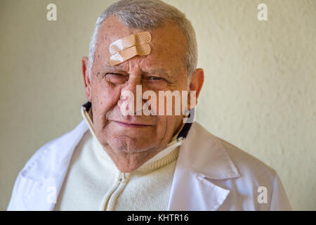 Il vecchio medico con patch sulla fronte Foto Stock