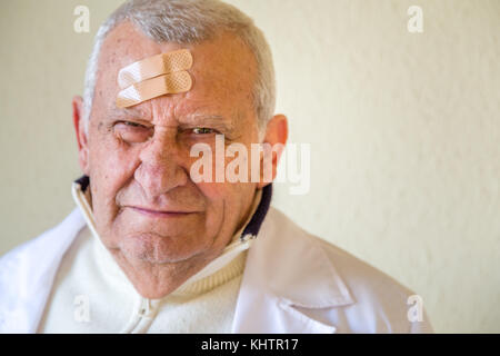 Il vecchio medico con patch sulla fronte Foto Stock