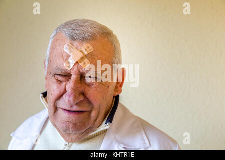 Triste vecchio medico con patch sulla fronte Foto Stock