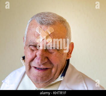 Triste vecchio medico con patch sulla fronte Foto Stock