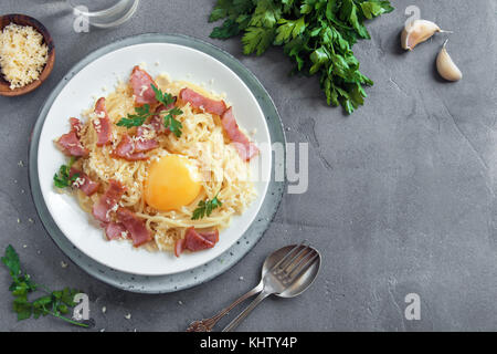 Spaghetti alla carbonara la pasta con la salsa di uova, pancetta e formaggio parmigiano grattugiato - le sane pasta italiana sul cemento grigio sfondo Foto Stock