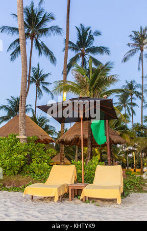 Due sedie a sdraio con ombrellone in spiaggia Foto Stock