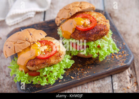 Due hamburger di pollo con le verdure su una tavola di legno Foto Stock