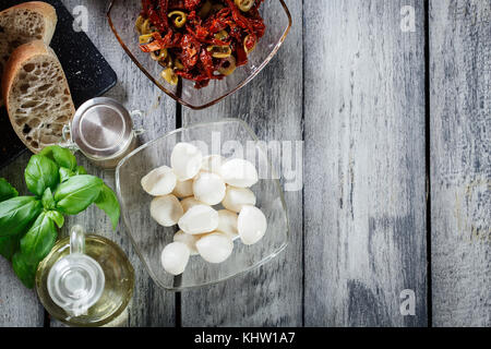 Ingredienti pronti per preparare la bruschetta con pomodori secchi e olive e formaggio. Cucina Italiana. Vista superiore Foto Stock