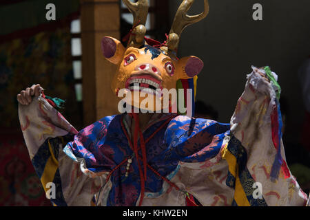 Monaco tibetano in cervo tantrico di maschera e costume rituale contro la parete del monastero, il Tibet. Foto Stock