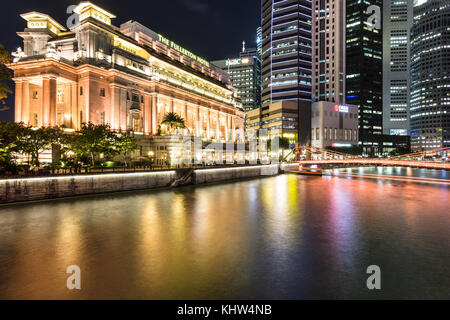 Singapore - 6 ottobre 2017: Le luci del famoso hotel Fullerton si riflettono nel fiume Singapore di fronte ai grattacieli del distretto finanziario Foto Stock