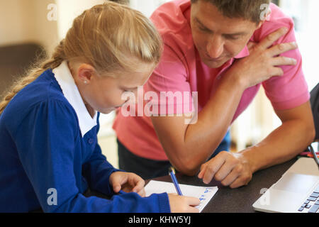 Padre aiutando la figlia con i compiti al banco di cucina Foto Stock