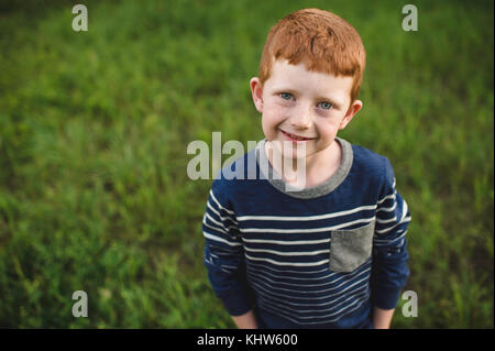 Ritratto di dai capelli rossi boy in piedi sull'erba Foto Stock