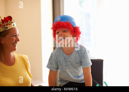 Madre e figlio giocare vestire, indossando cappelli divertenti, ridendo Foto Stock