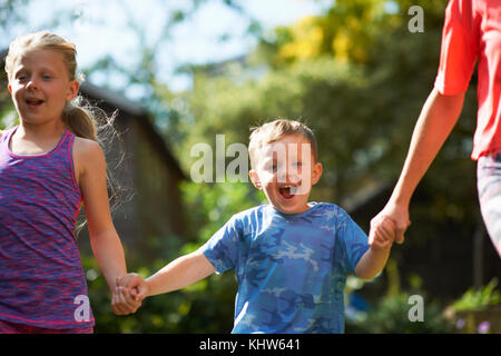 I fratelli tenendo le mani in esecuzione in giardino Foto Stock