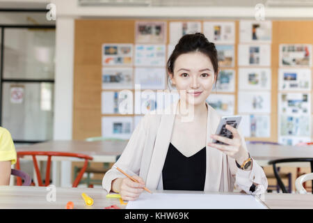 Studenti che lavorano utilizzando il telefono cellulare in classe Foto Stock