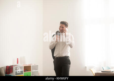 Giovane uomo che lavora da casa che fa chiamata dello smartphone Foto Stock