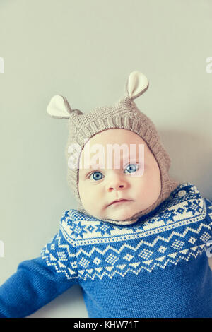 Ritratto di blue eyed baby boy in berretto lavorato a maglia con le orecchie Foto Stock