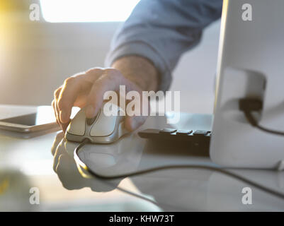 Imprenditore il canto su un mouse del computer lavoro in ufficio Foto Stock