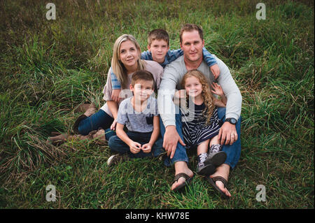 Famiglia di cinque godendo all'aperto sul verde campo erboso Foto Stock