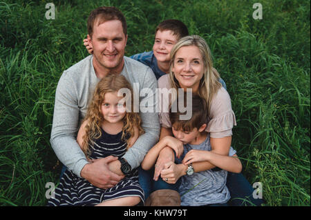 Famiglia di cinque godendo all'aperto sul verde campo erboso Foto Stock