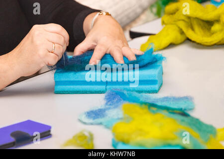 Mani femminili con un rullo ad aghi la loro lana in un modo a secco. Foto Stock