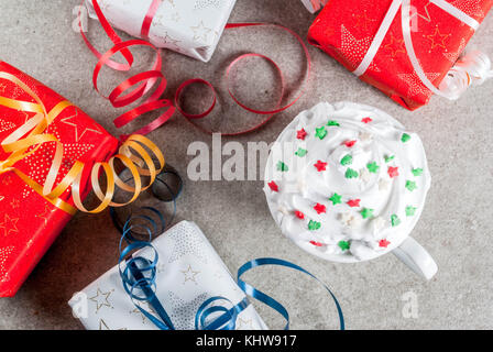 Natale e Anno nuovo concetto. regalo di Natale caselle e tazza di caffè o una cioccolata calda con panna montata e dolce stelle decorazione, sulla pietra grigia Foto Stock