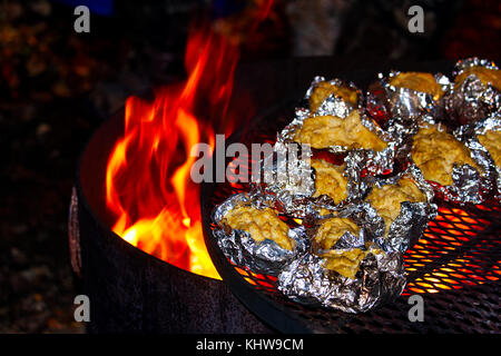 Fare ripiene Patate al forno durante la notte su un falò. Foto Stock