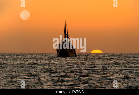 Ocean sunset nave silhouette è una vecchia nave di legno seduta in mare guardando il tramonto sull'oceano orizzonte. Foto Stock
