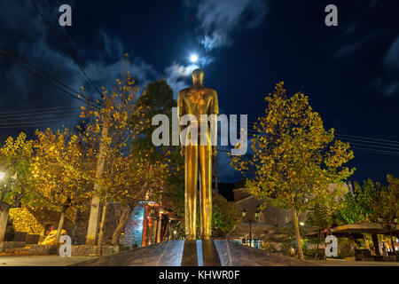 Una statua in bronzo che si trova nella piazza principale del villaggio di Vytina, nel Peloponneso, in Grecia, in una notte piena di luna. Foto Stock
