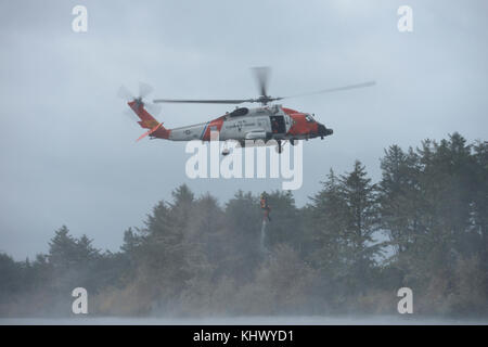 Petty Officer 2a classe Giordania Gilbert, una sopravvivenza di aviazione tecnico al Coast Guard Settore Columbia River, è issata fino in un MH-60 elicottero Jayhawk durante la ricerca e la dimostrazione di salvataggio presso gli Stati Uniti/Cina Disaster Management valuta detenute a Camp Rilea situato in Warrenton, Ore., nov. 16, 2017. Soldati di U.S. Pacifico esercito, Oregon Guardia Nazionale e la Repubblica popolare di Cina, Popolo della Esercito di Liberazione Teatro Sud Il comando ha preso parte nel XIII iterazione del cambio, che è progettato per condividere real-mondo lezioni apprese circa la fornitura di assistenza umanitaria e di disaster rel Foto Stock