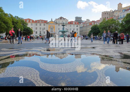 LISBONA, PORTOGALLO - 2 NOVEMBRE 2017: Riflessi dopo la pioggia sul marciapiede acciottolato di Piazza Rossio con una fontana e facciate colorate Foto Stock