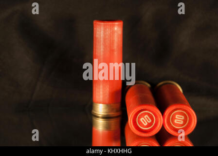 Tre rossi shot-cartucce caricate da un fucile da caccia, su sfondo scuro Foto Stock
