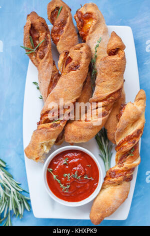 Gustoso formaggio bastoni con pancetta, erbe e salsa di pomodoro. top view, sfondo blu. carne formaggio snack per la birra e il concetto di partito, la Giornata del ringraziamento. Foto Stock