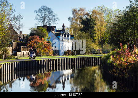 Paio di spingere un passeggino camminando sul canal alzaia in vigne Parco in autunno. Droitwich Spa, Worcestershire, Inghilterra, Regno Unito, Gran Bretagna Foto Stock