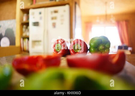 Intero e metà peperoni rossi e verdi sul banco di cucina Foto Stock