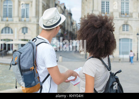 Vista posteriore del giovane azienda libro guida in città Foto Stock