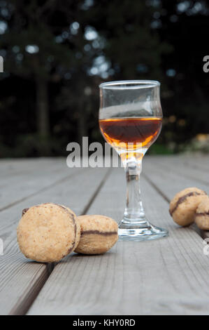 Lady's baci - italiana di nocciole cookies sandwich con un bicchiere di tipico liquore siciliano Foto Stock