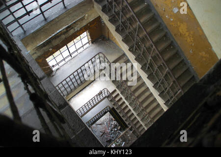 Abbandonato e distrutto le scale nella vecchia fabbrica. Dimenticato la scala con peeling di vernice sulla parete. Foto Stock