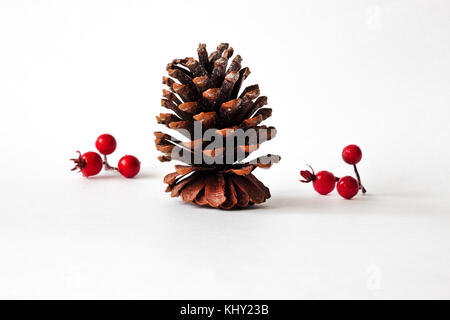 Composizioni di natale con cono di pino decorazioni e bacche di vischio su sfondo bianco in orizzontale Foto Stock