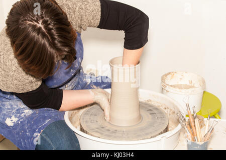 Potter femmina creando un vaso di terracotta su un tornio del vasaio Foto Stock