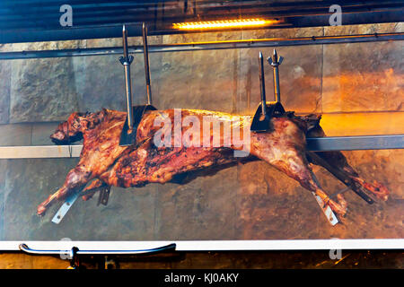 Carcassa di agnello su spiedino dietro il vetro in forno Foto Stock