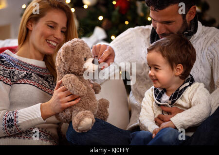 I genitori svolgono con suo figlio con Teddy bear su vacanze di natale Foto Stock