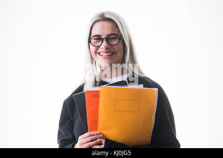 Istruzione secondaria nel Regno Unito: Una giovane adolescente felice sorridente, 16, 17 anni, studentessa che indossa gli occhiali, che va all'università con i suoi quaderni e i compiti tra le braccia, Regno Unito Foto Stock