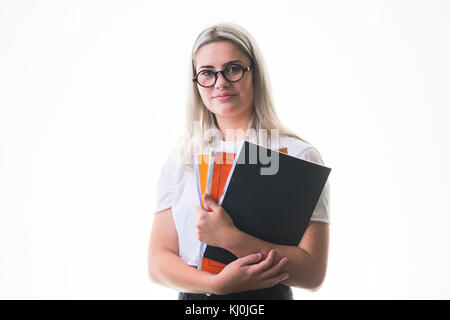 Istruzione secondaria nel Regno Unito: una giovane ragazza adolescente, 16, 17 anni, studente allievo indossando occhiali, andando a scuola college con il suo notebook compiti di lavoro nelle sue braccia, Regno Unito Foto Stock