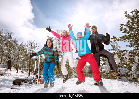 La famiglia felice sul salto con sci sulla neve in montagna Foto Stock