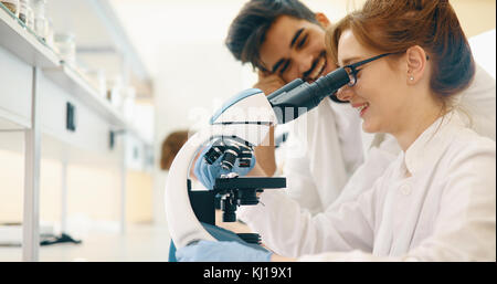 Gruppo di scienziati facendo ricerca guardando attraverso il microscopio Foto Stock