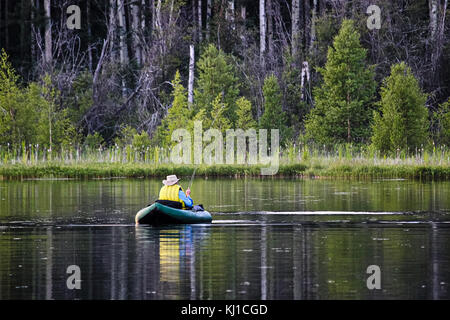 Vista posteriore di un uomo sconosciuto pesca a mosca utilizzando un tubo galleggiante. Foto Stock