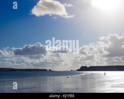 Un uomo cammina da solo con il suo cane sulla vasta spiaggia sud Tenby Pembrokeshire in una giornata di sole Foto Stock