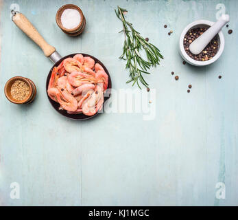 Cucina asiatica ingredienti freschi con piccoli gamberi in una piccola padella, erbe aromatiche e pepe su legno sfondo blu vista dall'alto bordo, posto per il testo Foto Stock